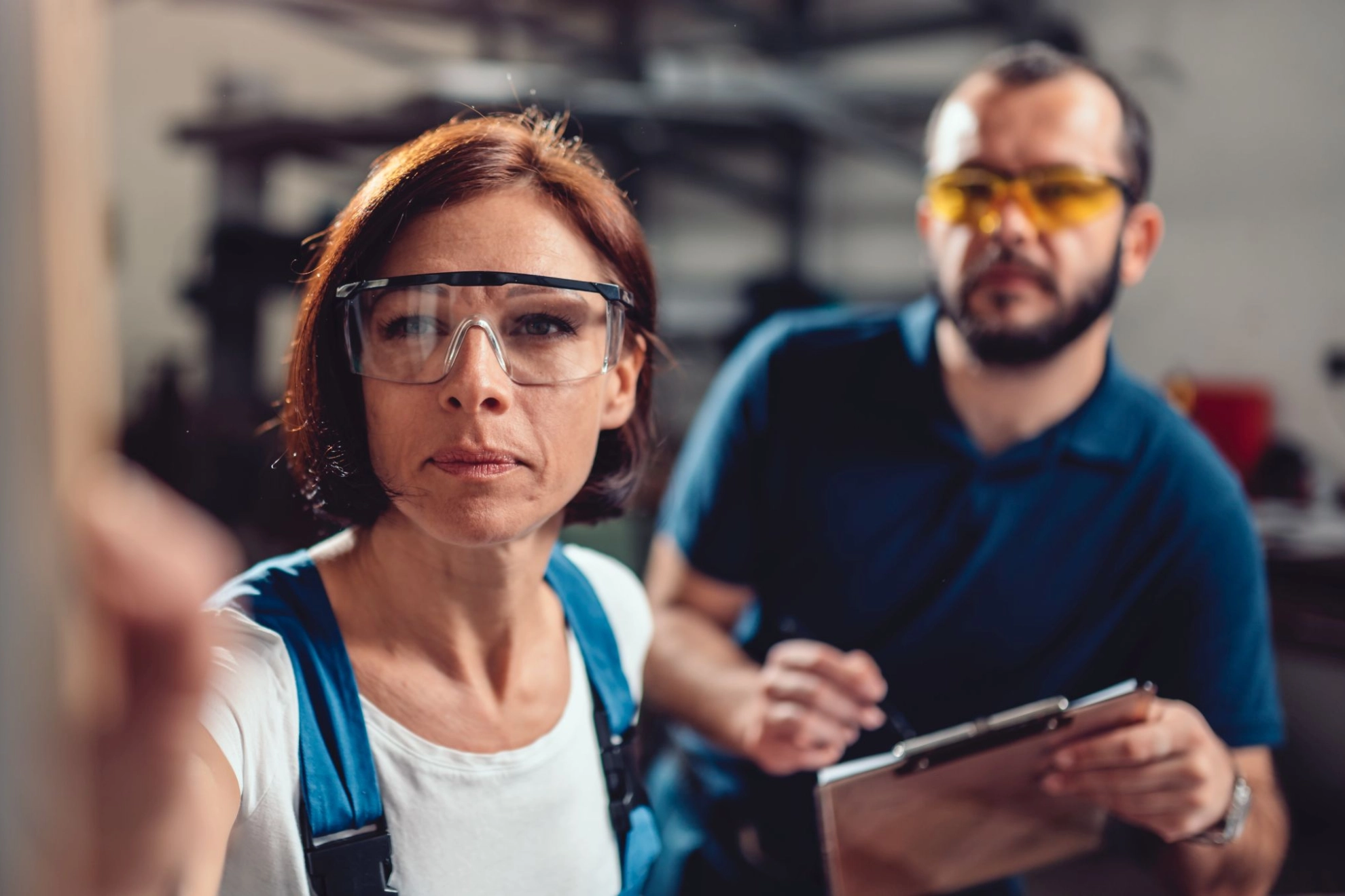 Arbeitnehmerin und Arbeitnehmer prüfen gemeinsam eine Maschine oder Bestand